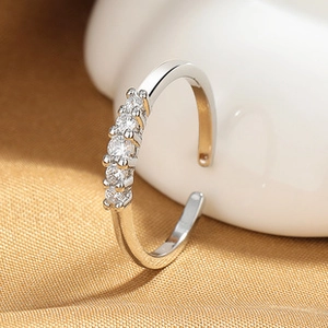 Detalle macro del anillo ajustable plateado con cinco circonitas brillantes en satén