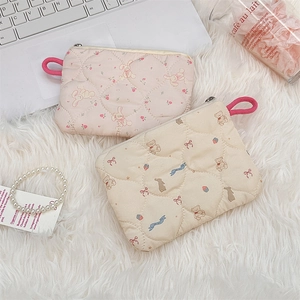 Detailed quilted makeup bags with rabbit and teddy bear prints on plush white background