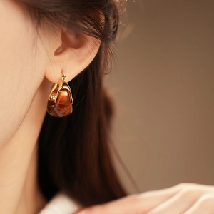Close-up of model wearing a gold-plated brown resin hoop earring with amber finish