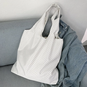 Detailed view of large vintage polka dot canvas tote bag resting on a gray sofa
