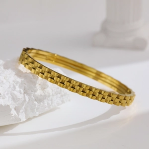 Close-up of golden stainless steel bracelet featuring a textured three-layer gear watchband design