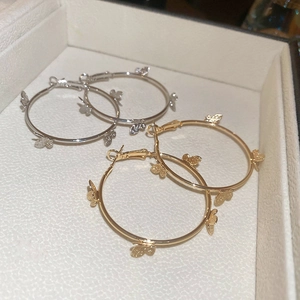 Close-up of gold and silver butterfly hoop earrings on a textured jewelry tray