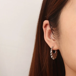 Gros plan sur des boucles d'oreilles créoles en acier argenté portées par un mannequin