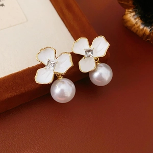 Macro shot of white flower earring with square crystal and large hanging pearl detail