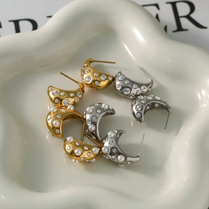 Detailed macro view of 18k gold crescent earrings with rhinestones and white pearls
