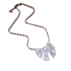 Elegante collana con ciondolo a fiocco argentato e zirconi lucidi su sfondo bianco