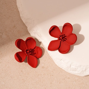 Minimalist red flower stud earrings with matte finish on elegant stone pedestal