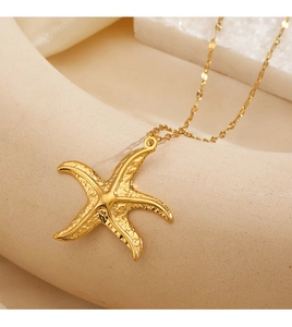Detailed view of a textured golden starfish pendant on a delicate link chain necklace