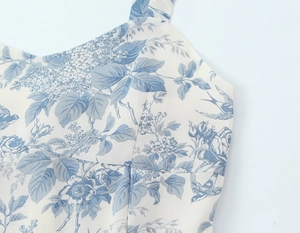 Close-up of blue floral and bird print on white fabric with thin shoulder strap detail
