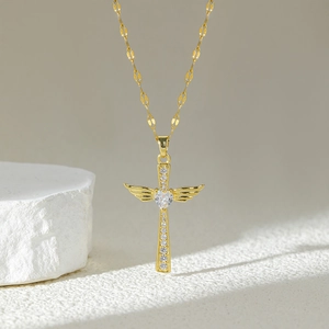 Gold angel wing cross necklace with heart crystal pendant on white stone base