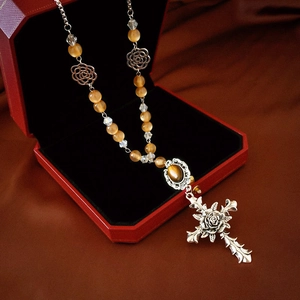 Detailed macro view of vintage tiger eye beaded necklace with silver rose cross pendant