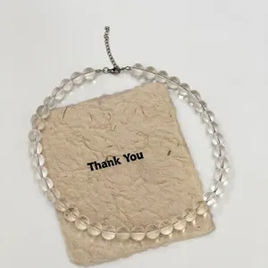 Minimalist summer clear crystal glass bead necklace with silver lobster clasp on a beige card