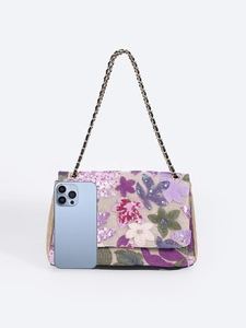 Macro view of floral embroidery and sequins on the beige shoulder bag with chain strap