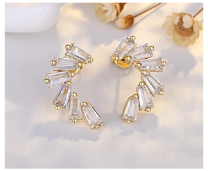 Macro shot of gold crescent earrings with rectangular cubic zirconia on a textured surface