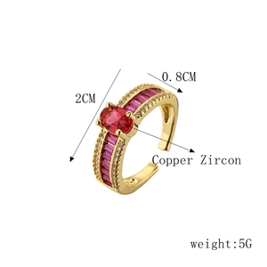 Detail view of gold finish ring with red zircon and copper specs, 2cm diameter size