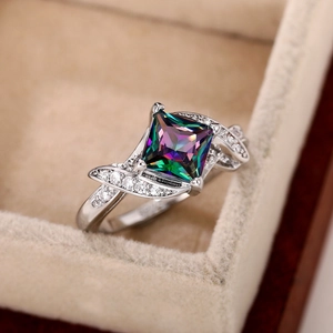 Macro detail of silver ring with square rainbow stone in beige velvet jewelry box
