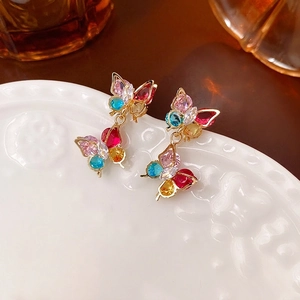 Elegante vergoldete Schmetterlingsohrringe mit bunten Zirkonia-Steinen auf Keramikplatte