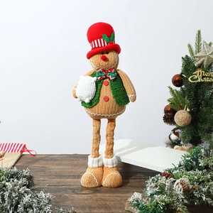 Detail of extendable gingerbread man doll with knitted vest on wooden table setup