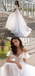 Detail of off-shoulder lace sleeves and layered tulle skirt on a white wedding dress