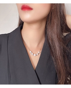 Close-up of minimalist freshwater pearl necklace with silver beads on a model's neck