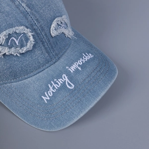 Dettaglio del ricamo sulla visiera del berretto da baseball in denim lavato