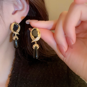 Detail of vintage gold-edged black teardrop earrings with crystals worn by a model