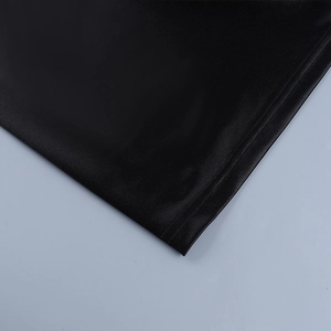 Détail de l'ourlet en tissu noir brillant et des coutures d'une mini robe de soirée