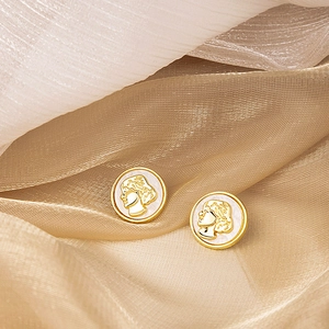 Detailed macro shot of vintage gold-framed cameo stud earrings with white portrait relief