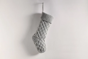 Detail einer grauen Strick-Weihnachtssocke mit Rautenmuster auf weißem Hintergrund