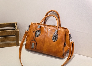 Detail of caramel oil wax leather bag featuring woven handles and silver hardware