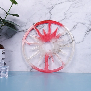 Close-up of circular resin coaster featuring red gradient glitter and sun cutout pattern