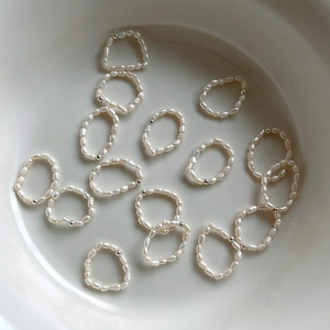 Macro shot of S925 silver baroque freshwater pearl elastic rings on white ceramic