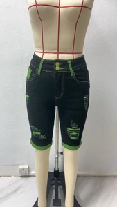 Detail von schwarzen Destroyed-Denim-Shorts mit neongrünem Kontrastbesatz und ausgefranstem Saum