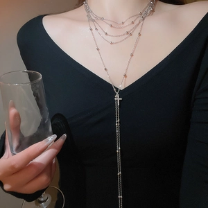 Macro detail of multi-layered silver cross necklace with zircons on an elegant model