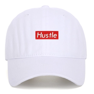 Close-up of red rectangle embroidery with white Hustle text on a washed baseball cap
