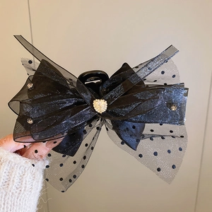 Détail de la pince à cheveux noeud noir avec résille à pois et strass en coeur