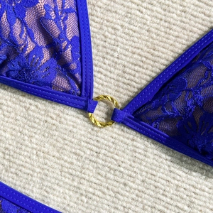 Detail of royal blue floral lace bikini top with a textured golden metal ring connector
