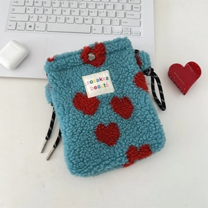 Detailed view of blue plush drawstring bag with red heart embroidery and metal buckle