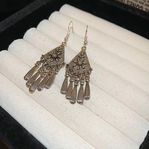Macro view of vintage silver rhombus earrings with five long metal tassel pendants