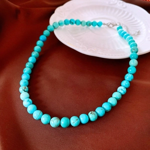 Détail d'un collier de perles turquoise avec fermoir mousqueton argenté et extension