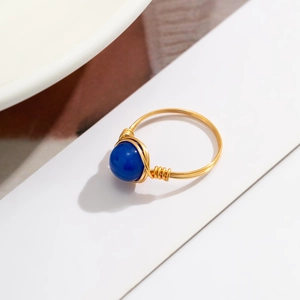 Detail of handcrafted gold wire wrapped ring featuring a vibrant blue opal stone bead