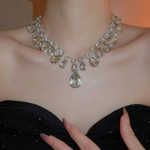 Detail view of a luxury sparkling waterdrop crystal pendant necklace on a female model
