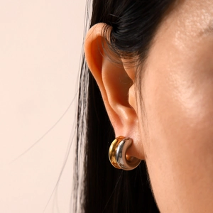 Macro view of bicolor 18K gold and silver chunky stainless steel hoop earrings on model