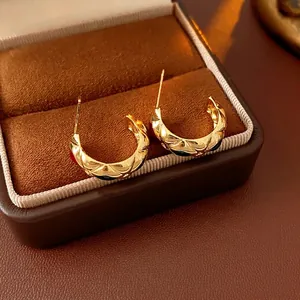 Vintage gold C-shaped quilted earrings displayed in a luxury brown jewelry case