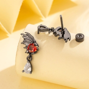 Gothic black dragon stud earrings with red heart zircon on a beige pedestal display