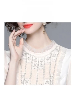 Détail de la robe en dentelle blanche avec broderie délicate et col à volants élégant