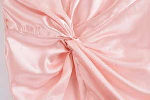 Nahaufnahme aus rosa Satin mit elegantem Knotendetail und drapierter Stoffstruktur
