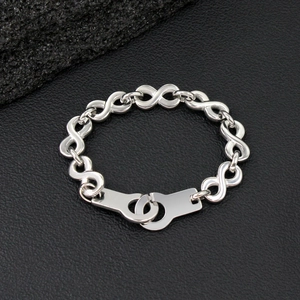 Macro detail of silver infinity link bracelet with handcuff clasp on dark stone