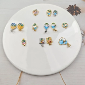 Detail of oil painting style enamel flower pendants in various shapes on a white tray