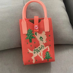 Close-up of coral orange knitted tote with deer patterns and LOVE button closure
